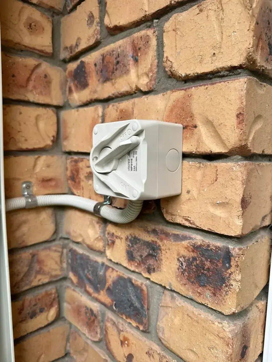 Weatherproof isolator switch mounted on a brick wall with conduit, installed by Electrikell Qld in the Gladstone region