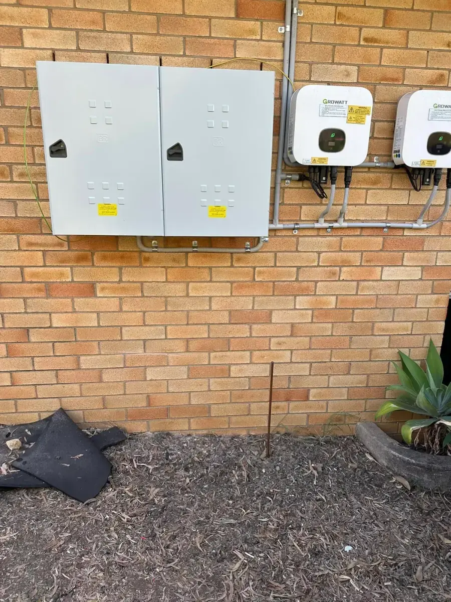 Two solar inverters and grey electrical enclosures mounted on a brick wall, connected by Electrikell Qld in the Gladstone region